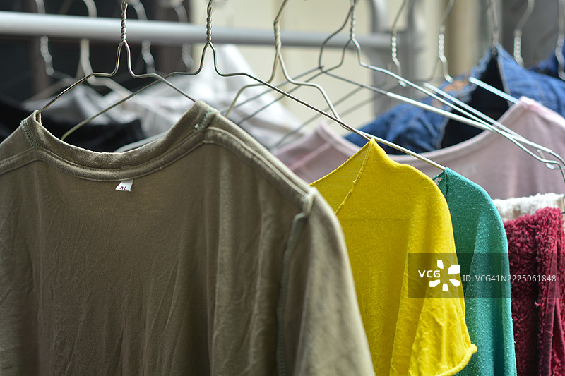 五颜六色的衬衫和裤子反面朝外挂在晾衣架上晾晒。图片素材