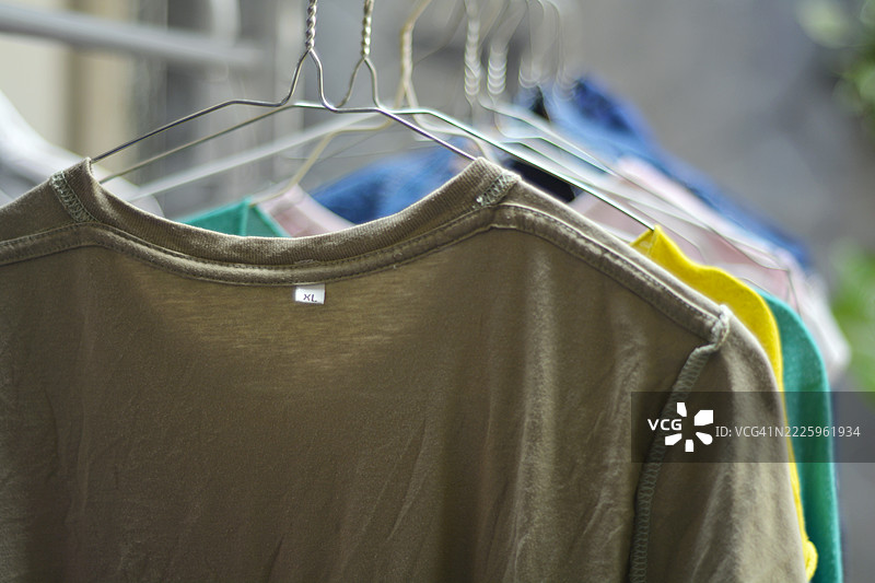 五颜六色的衬衫和裤子反面朝外挂在晾衣架上晾晒。图片素材