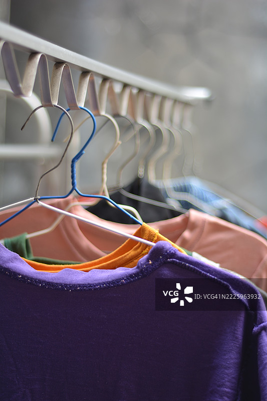 五颜六色的衬衫和裤子反面朝外挂在晾衣架上晾晒。图片素材