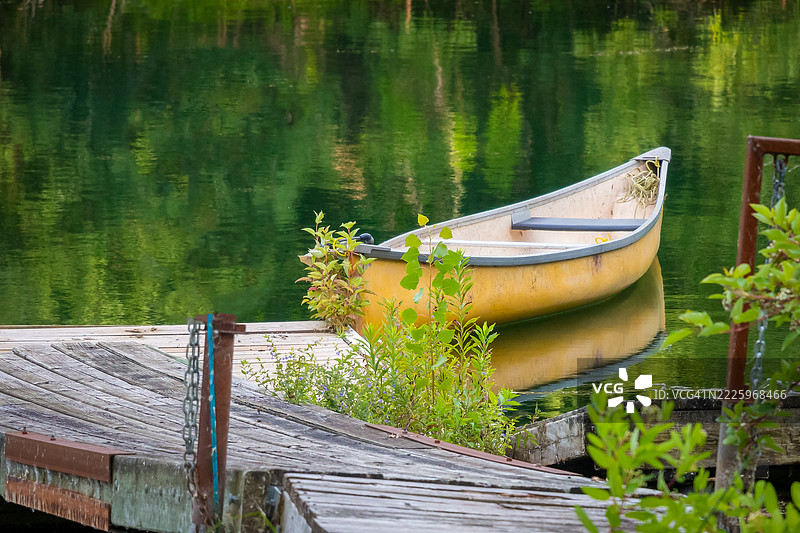 黄色独木舟停靠在宁静水面旁的木栈道上图片素材