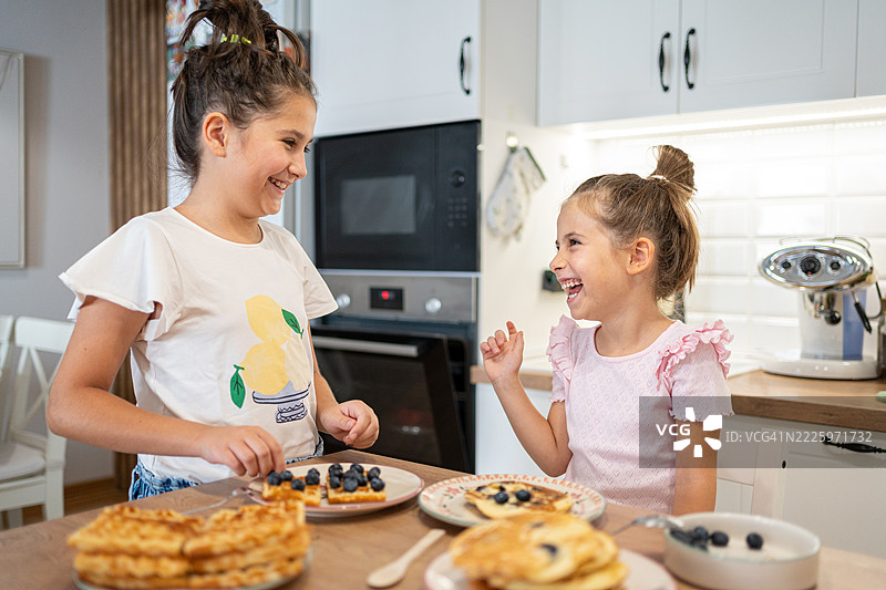 两个孩子在现代厨房享用蓝莓华夫饼早餐图片素材