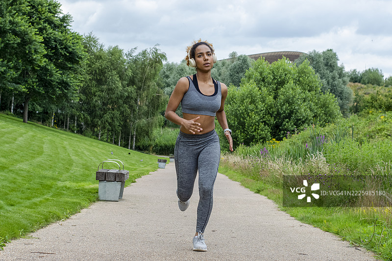 戴着耳机在大自然中慢跑的女性图片素材