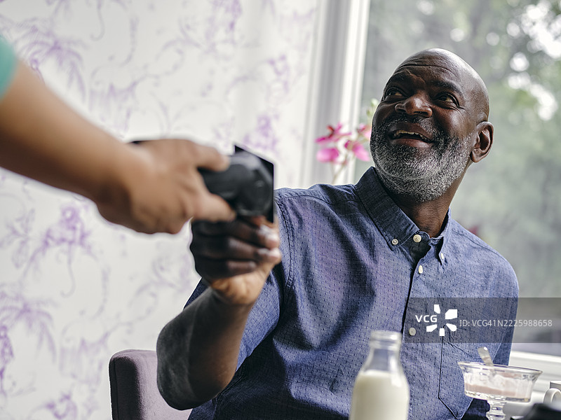 英国，微笑的男子在咖啡桌上用智能手机付款图片素材