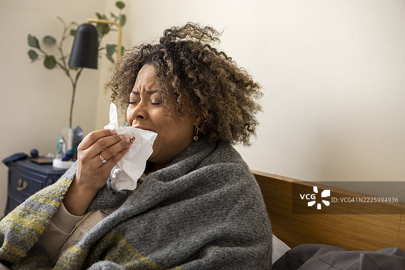 裹着毯子的女人在打喷嚏图片素材