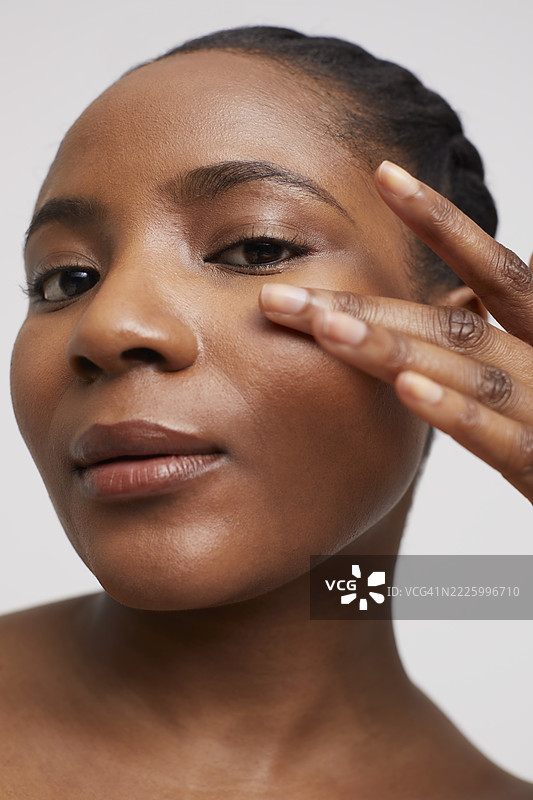 女性在工作室肖像中轻触脸庞图片素材