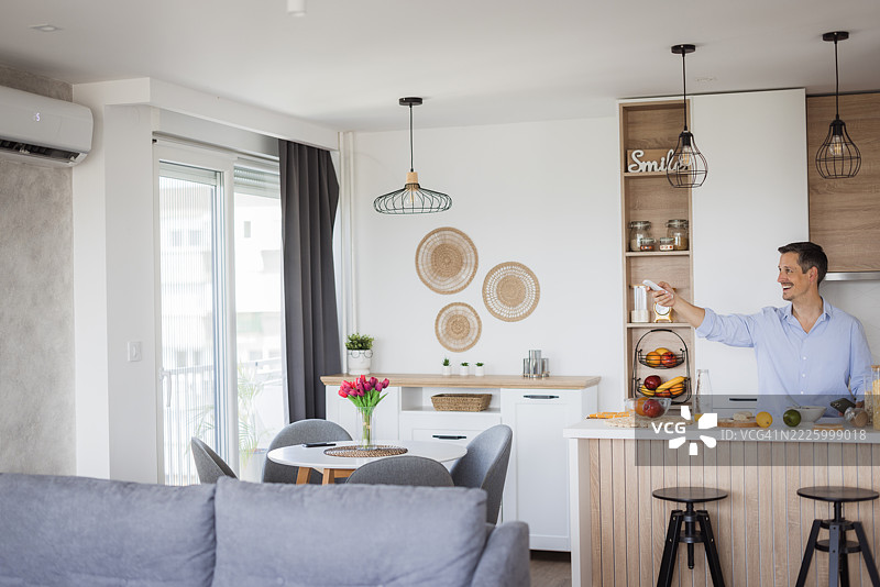 男子在现代公寓厨房中开启空调，抵御夏季热浪图片素材