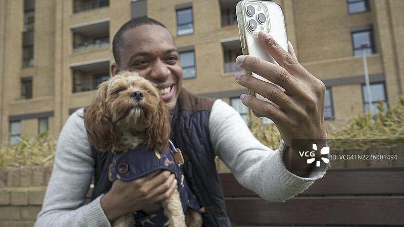 男人与狗一起用智能手机自拍图片素材