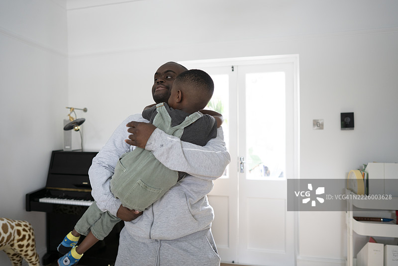 一位患有唐氏综合症的男子抱着一个4-5岁的男孩图片素材