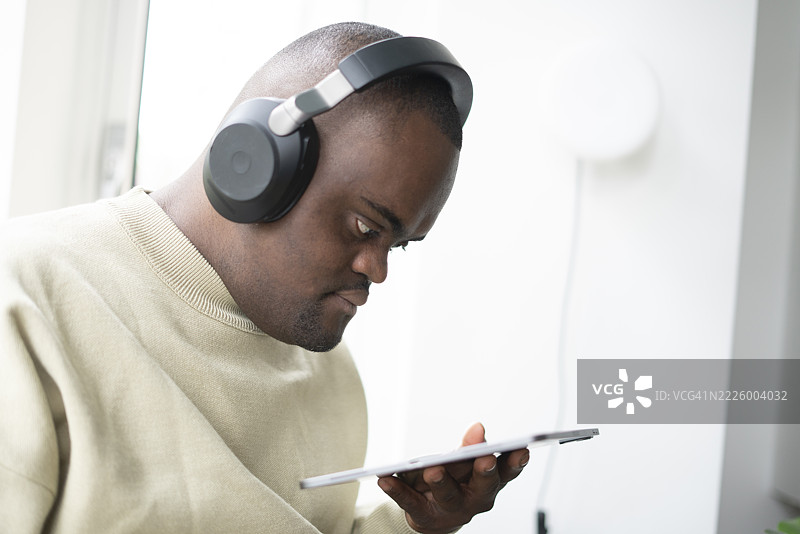 戴着耳机、使用平板电脑的唐氏综合症男性图片素材