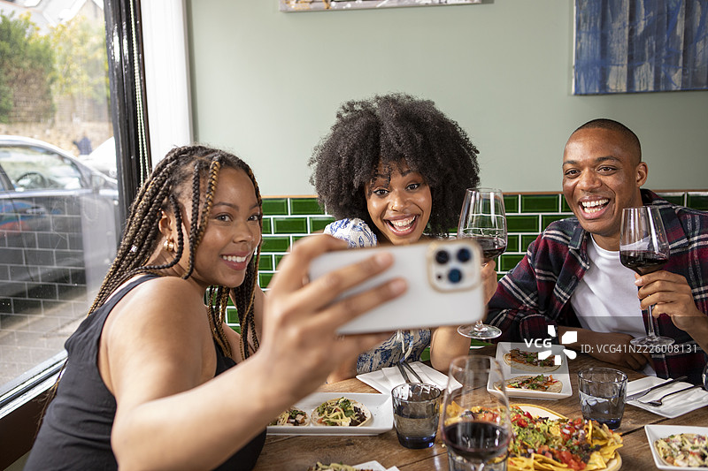 英国，伦敦，微笑的朋友们在餐厅桌子上自拍图片素材