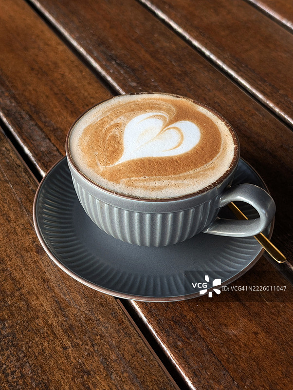 一杯心形艺术的卡布奇诺放在木桌上图片素材