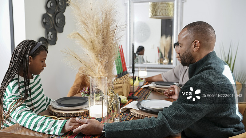 一家有孩子（8-9岁，12-13岁）在庆祝宽扎节的餐前祈祷图片素材