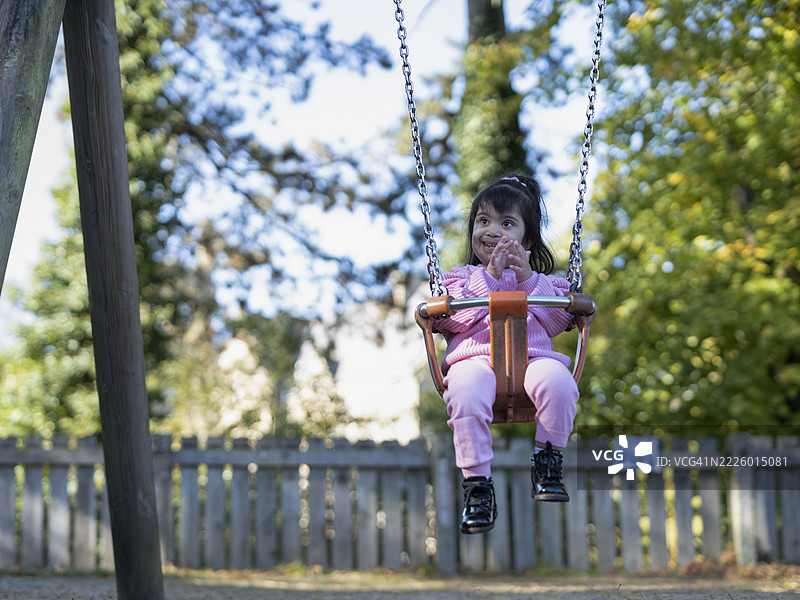 在游乐场上荡秋千的唐氏综合症女孩图片素材