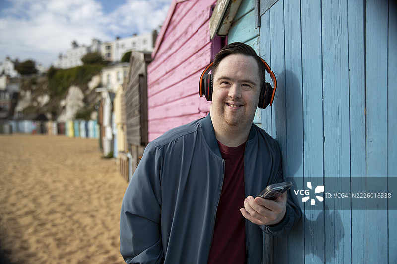 戴着耳机、手持智能手机的男子肖像图片素材