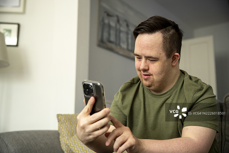 男人坐在沙发上使用智能手机图片素材