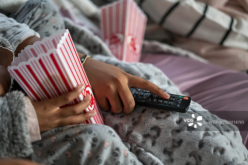 姐妹们手持遥控器和爆米花的特写镜头图片素材