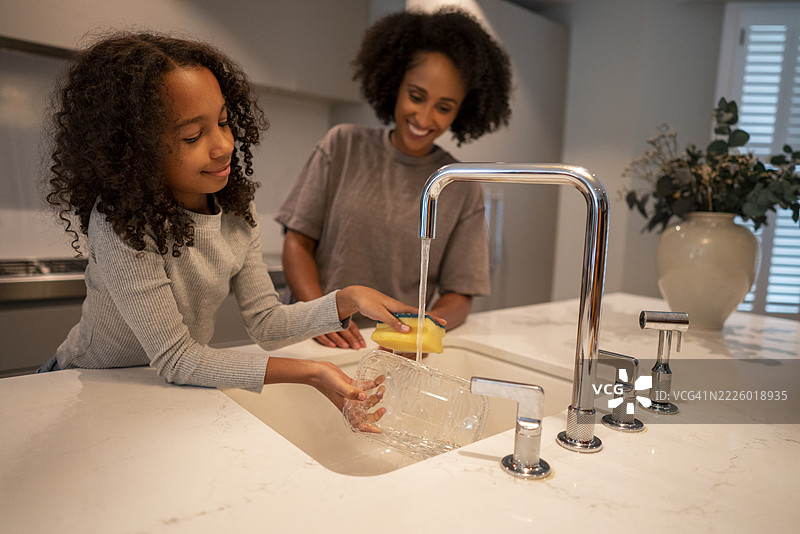 微笑的母亲在厨房帮助女儿洗碗图片素材