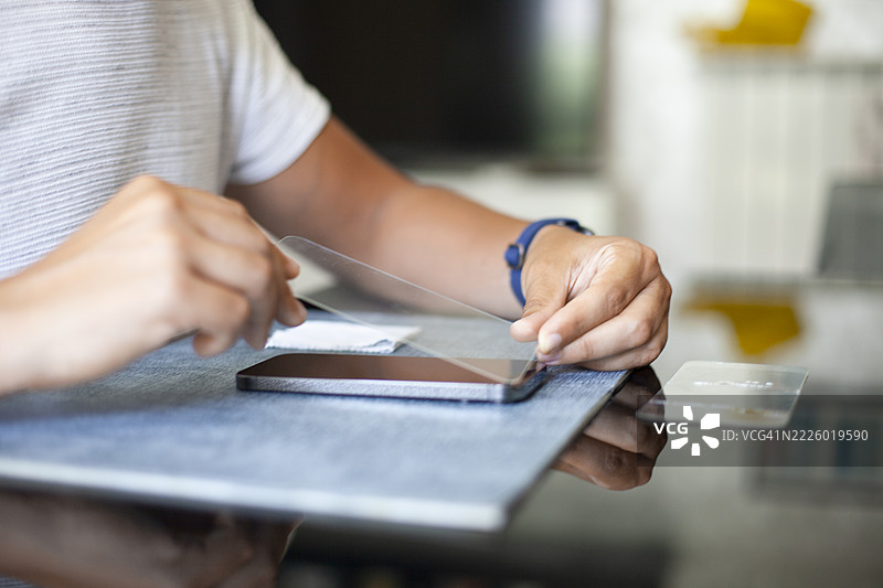 男子在更换玻璃后为智能手机贴上新屏幕保护膜图片素材