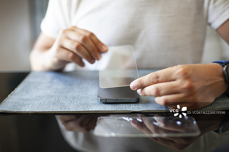 男子在更换玻璃后为智能手机贴上新屏幕保护膜图片素材
