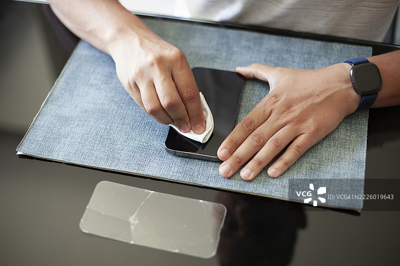 男子在拆除屏幕保护膜后用布清洁智能手机图片素材