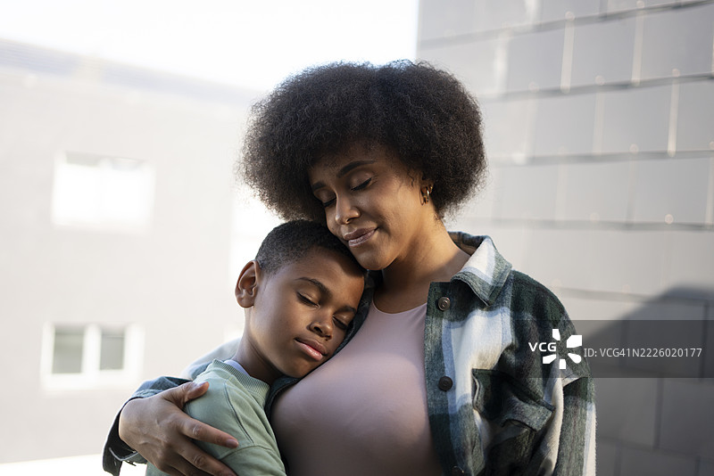 微笑的母亲和儿子拥抱在一起图片素材