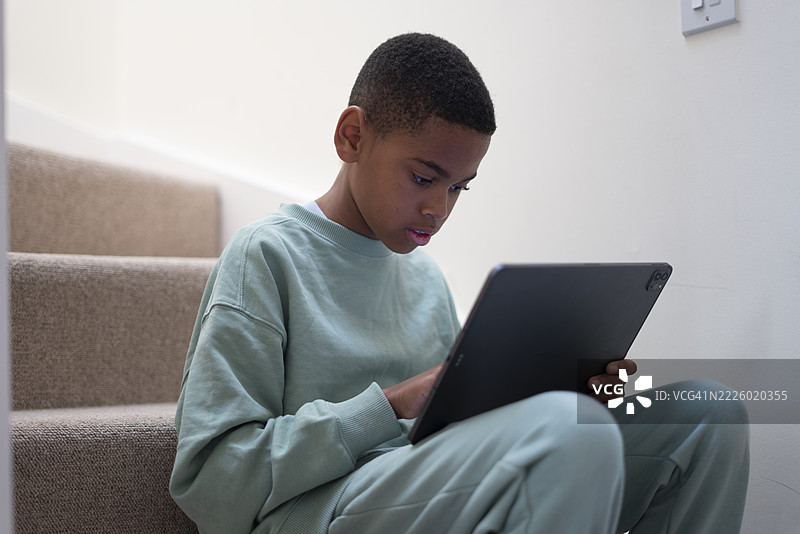 男孩坐在楼梯上使用平板电脑图片素材