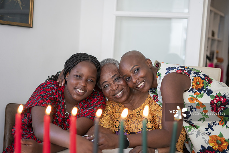 少女与母亲和祖母在桌子旁，桌上摆放着宽扎节的蜡烛。图片素材