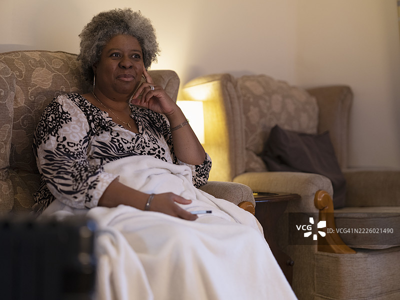 女人坐在毯子下看电视图片素材