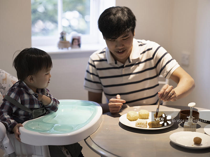 父亲和婴儿儿子在家制作月饼图片素材