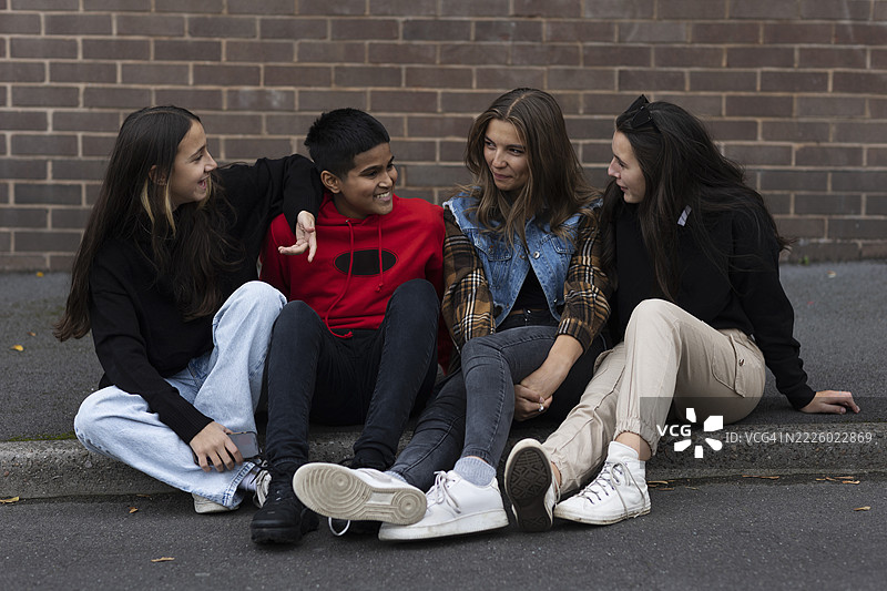 微笑的朋友们坐在人行道上交谈图片素材