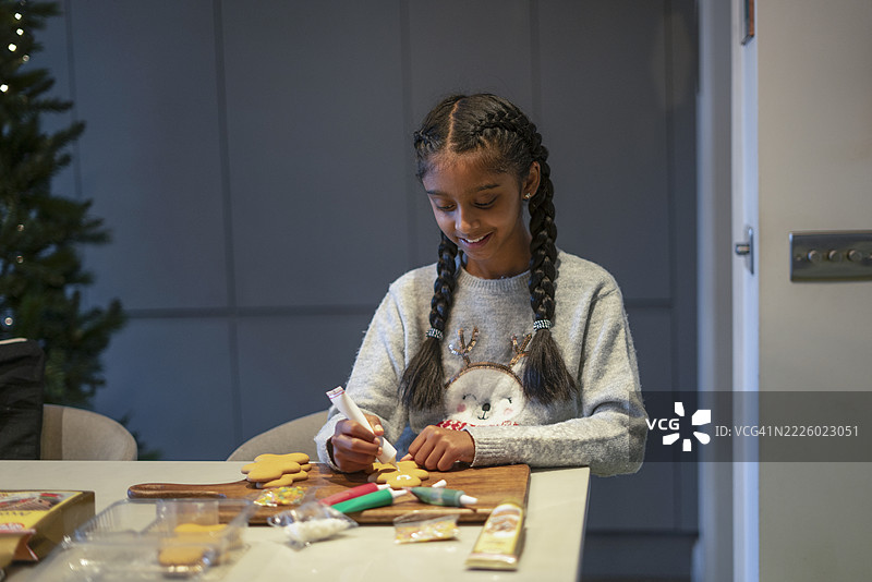 微笑的女孩在厨房装饰姜饼饼干图片素材