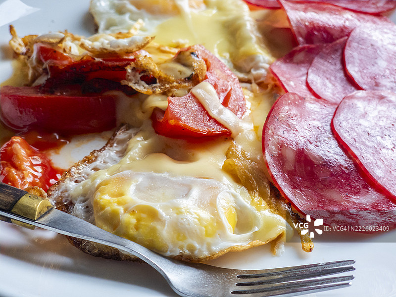 早餐：煎蛋配融化的奶酪、西红柿和意大利香肠图片素材