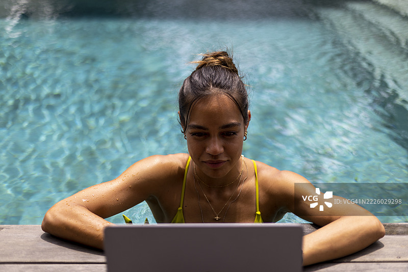 女人在游泳池放松时使用笔记本电脑图片素材