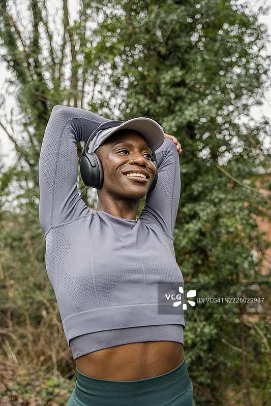 微笑的运动女性在公园里伸展手臂图片素材