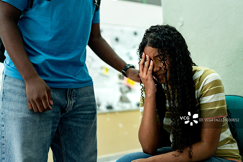 学生因头痛或悲伤表情在学校接受同事的支持图片素材