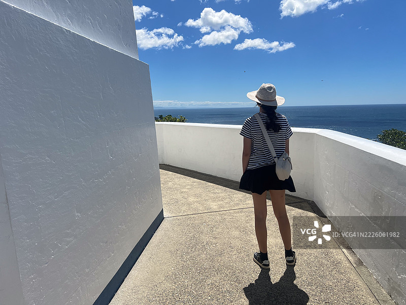 少女在夏季假期中走到海边的瞭望台。图片素材