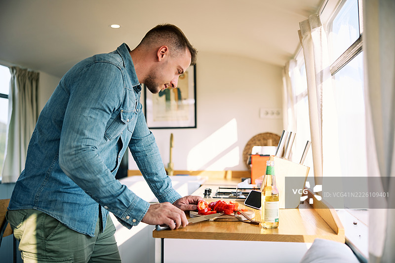 男子在明亮的厢式车厨房中准备午餐图片素材