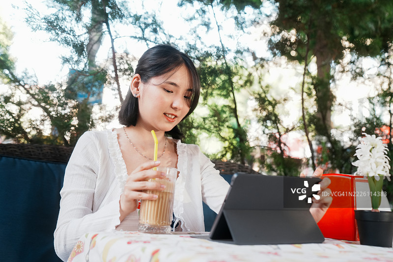 年轻女性在咖啡店使用平板电脑图片素材