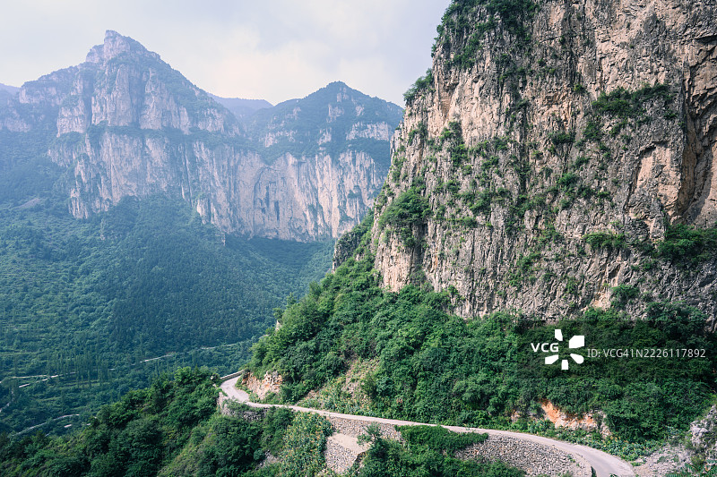 蜿蜒的山路穿过郁郁葱葱的山谷图片素材