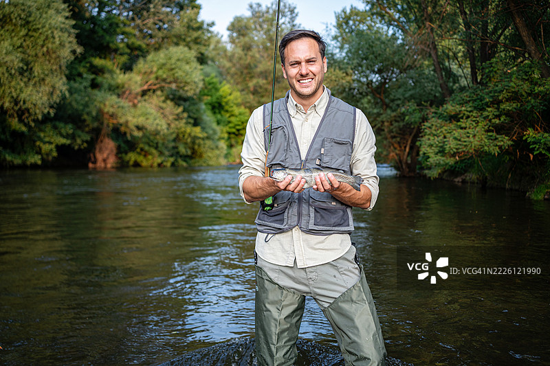 男子在宁静的河流环境中微笑着飞钓图片素材