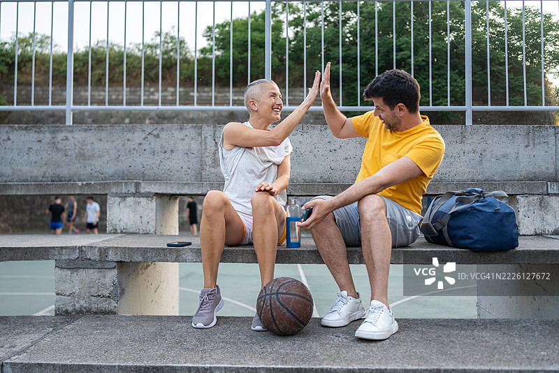 中年朋友们在阳光明媚的日子里享受户外篮球和友谊图片素材