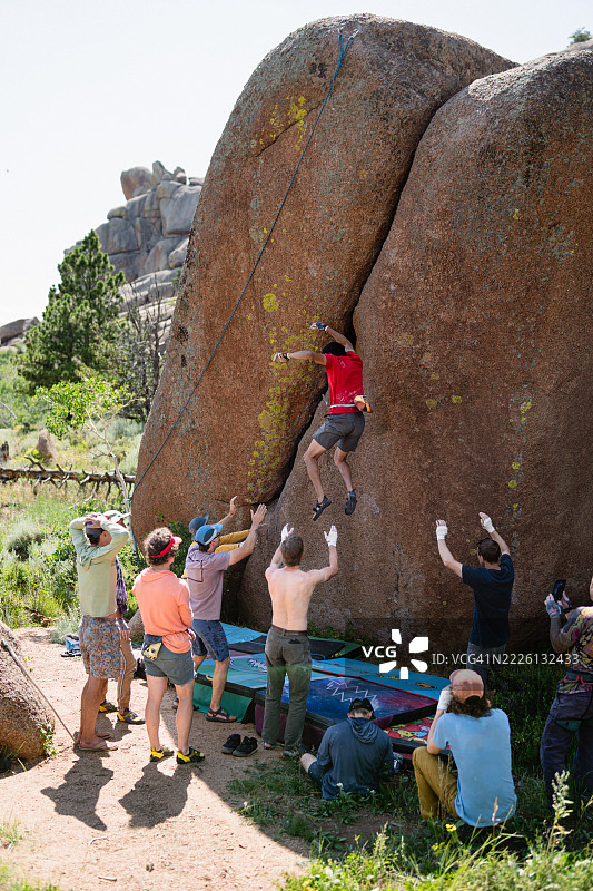 阳光明媚的下午，男人与朋友们一起攀岩，途中摔倒。图片素材