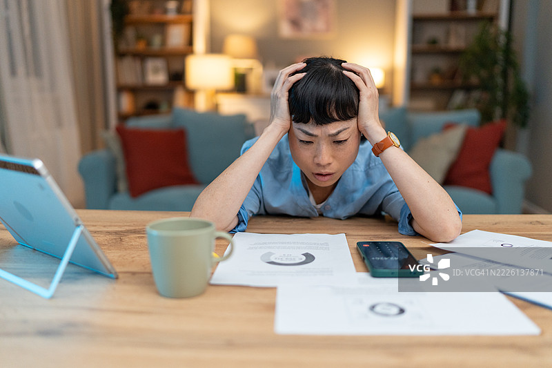 感到压力的亚洲自由职业者在家工作时头痛图片素材
