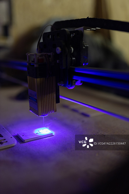 激光雕刻机在运作中，蓝色光束特写镜头图片素材