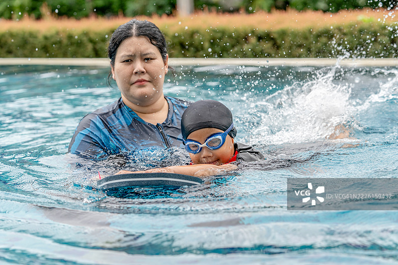 快乐的小运动员在母亲的陪伴下上游泳课 - 活泼的小男孩在蓝色泳池中与母亲一起享受游泳的乐趣。家庭生活方式。图片素材