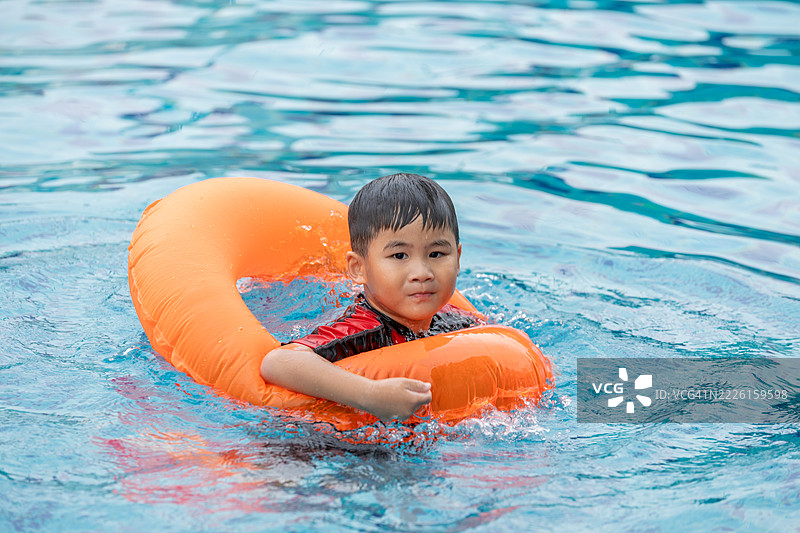 孩子在游泳池里坐在充气浮圈上。水上玩具，健康的户外运动活动。孩子们的海滩乐趣。孩子在夏季水池中嬉水。图片素材