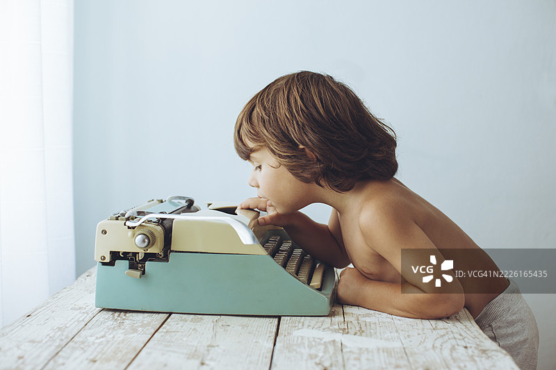 好奇的孩子在阳光明媚的房间里探索复古打字机，享受宁静的下午时光。图片素材