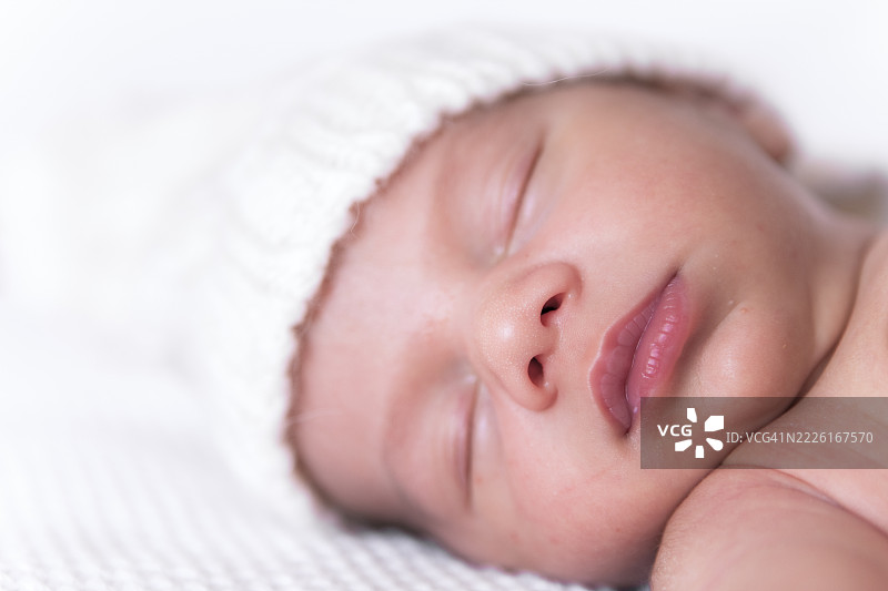 可爱的新生儿安静地在温暖的帽子里睡觉图片素材