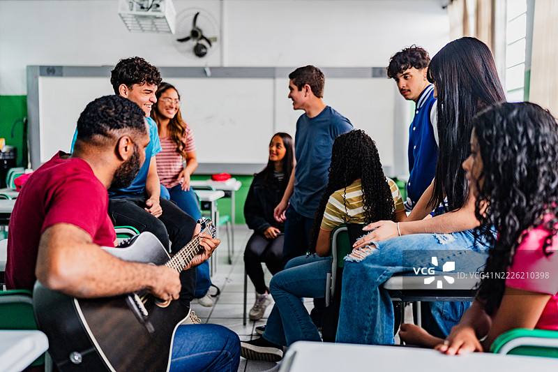 音乐老师在教室里给高中生上吉他课图片素材