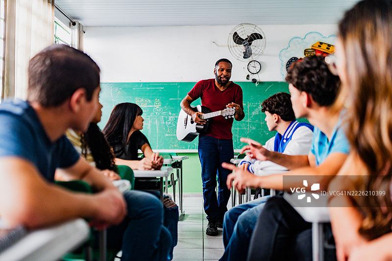 音乐老师在教室里给高中生上吉他课图片素材